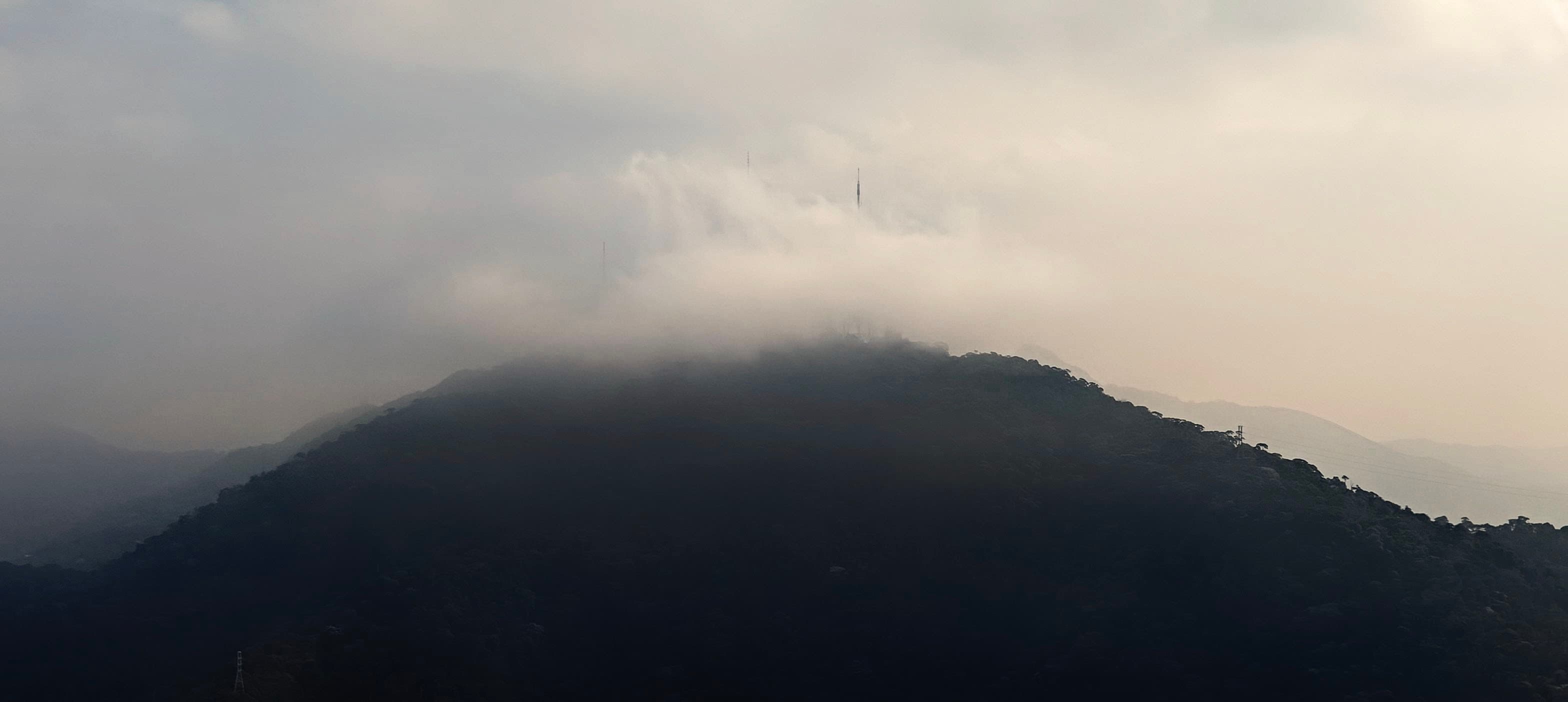 Low cloud draped over a dark forested ridge near Corcovado, with pale sky behind it.