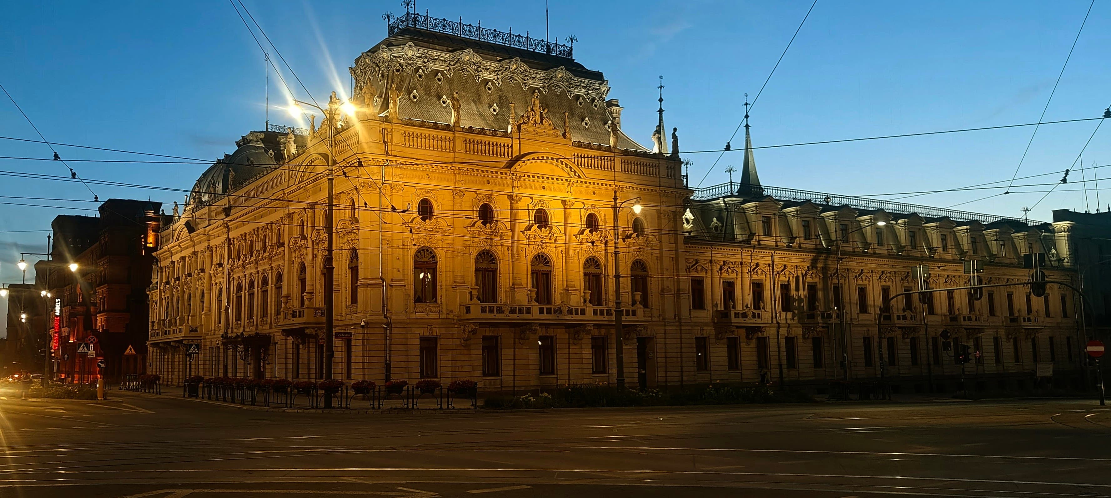 Illuminated Izrael Poznański Palace at night beside the Manufaktura complex in Łódź.