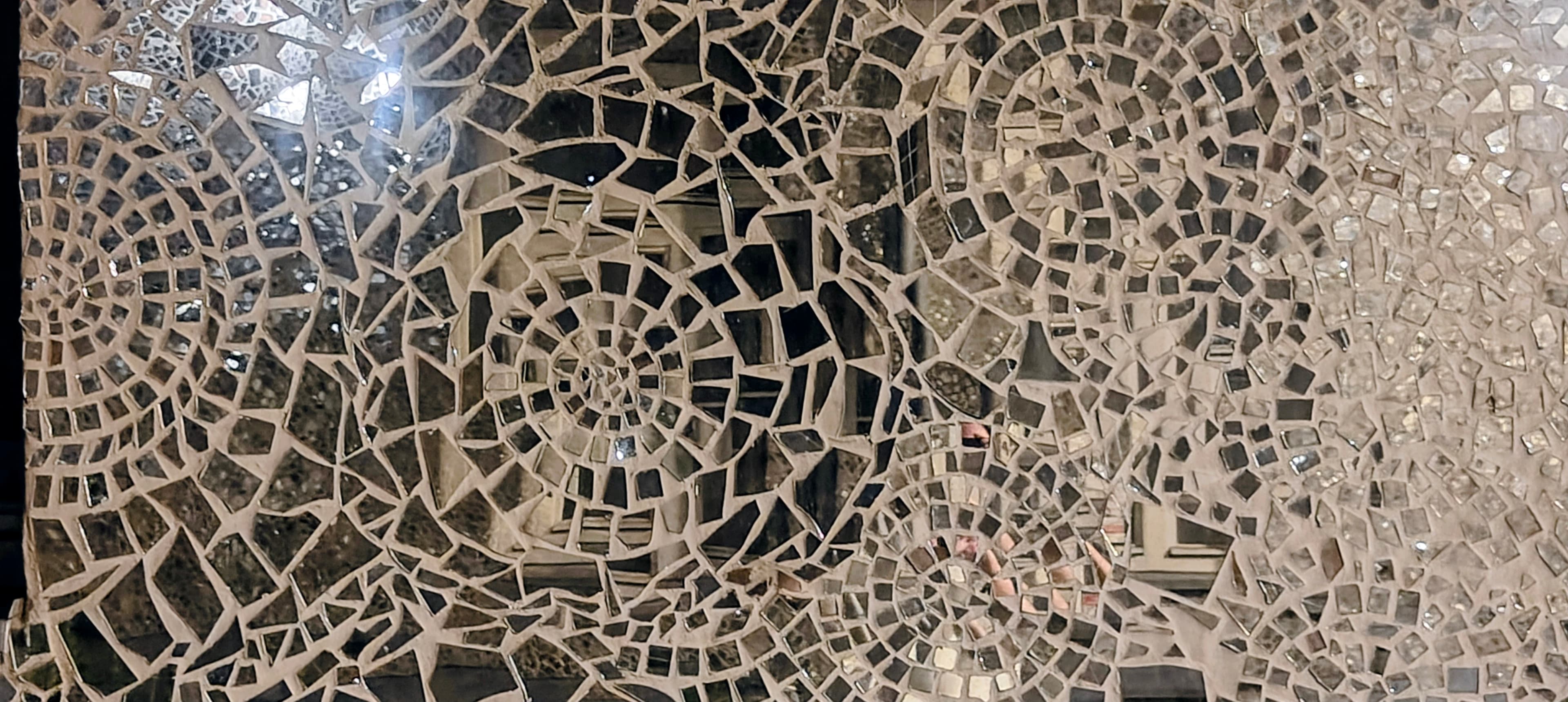 Close-up of irregular mirror fragments forming the mosaic walls of Pasaż Róży.