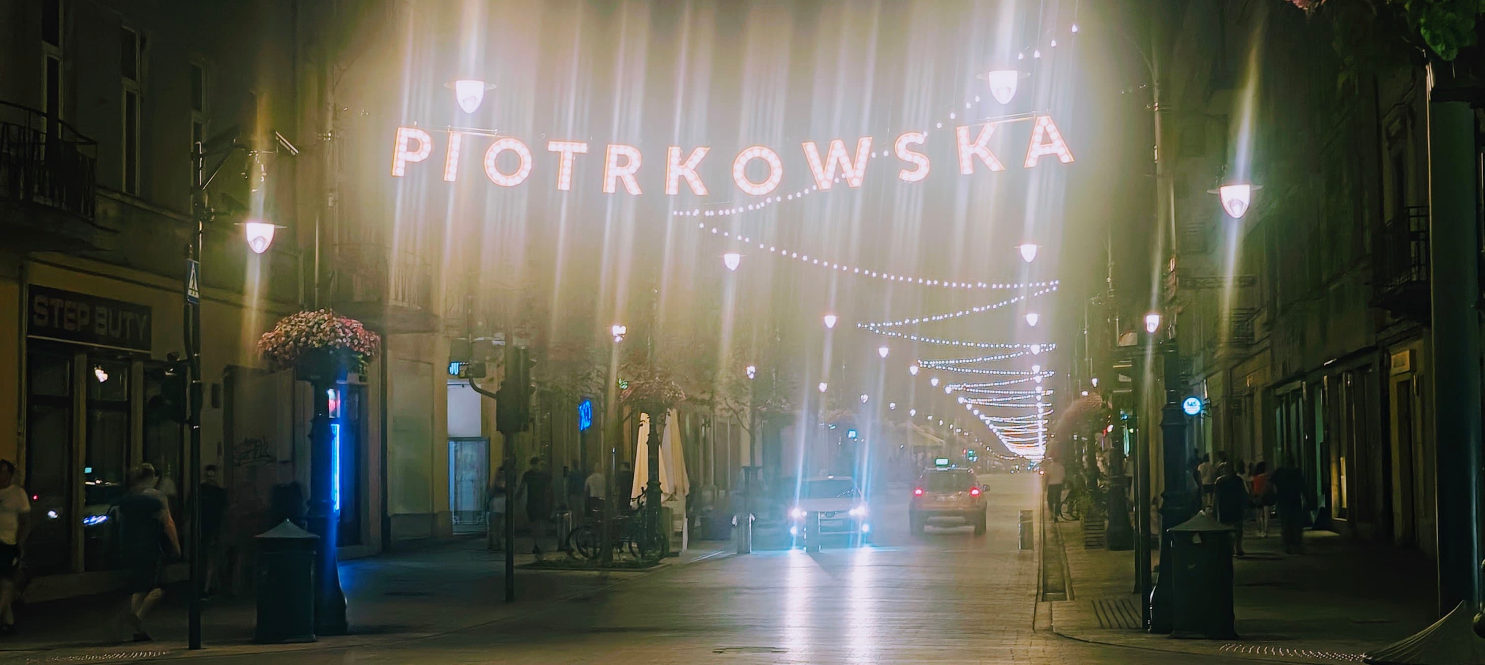 Illuminated Piotrkowska sign above the pedestrian street at night in central Łódź.