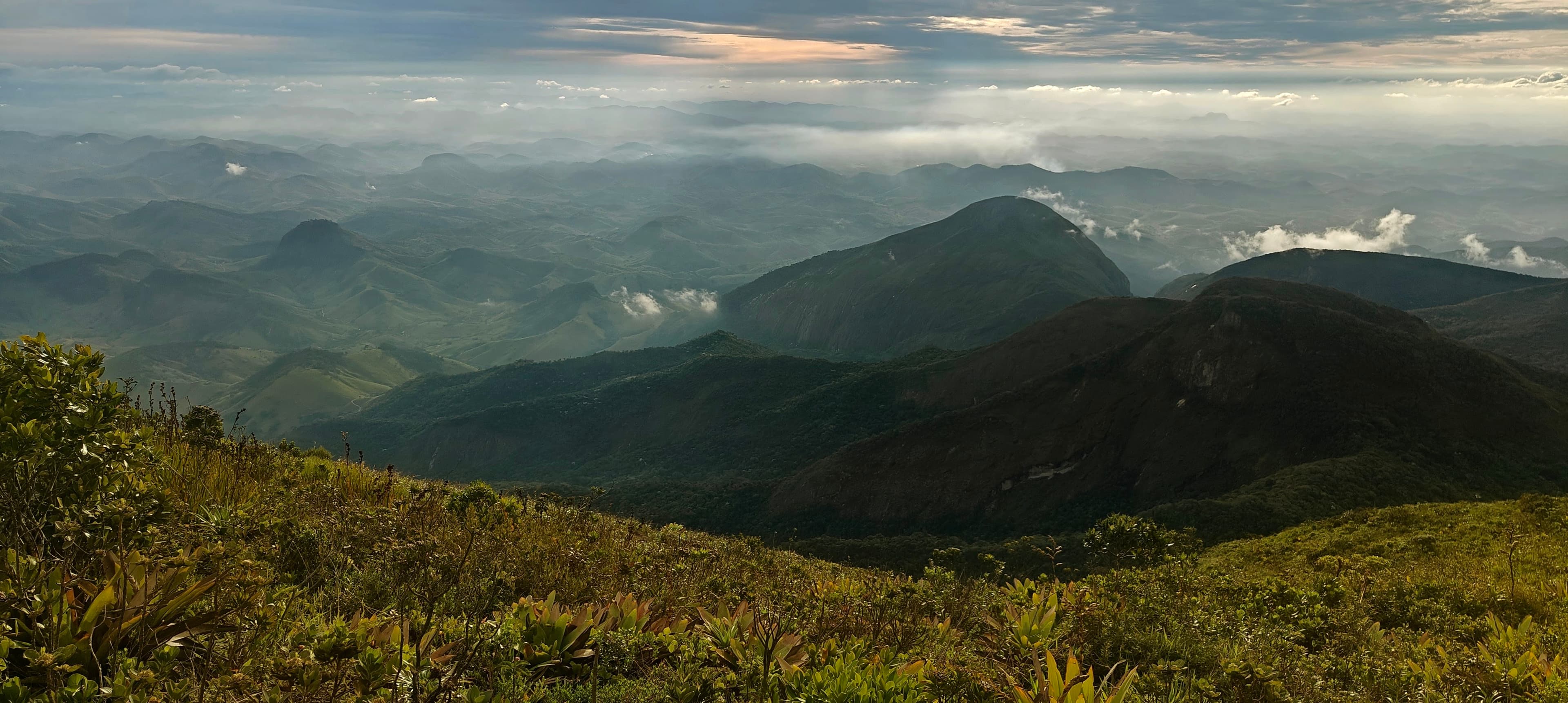 Dark green mountain ridges fading into cloudy distant hills.