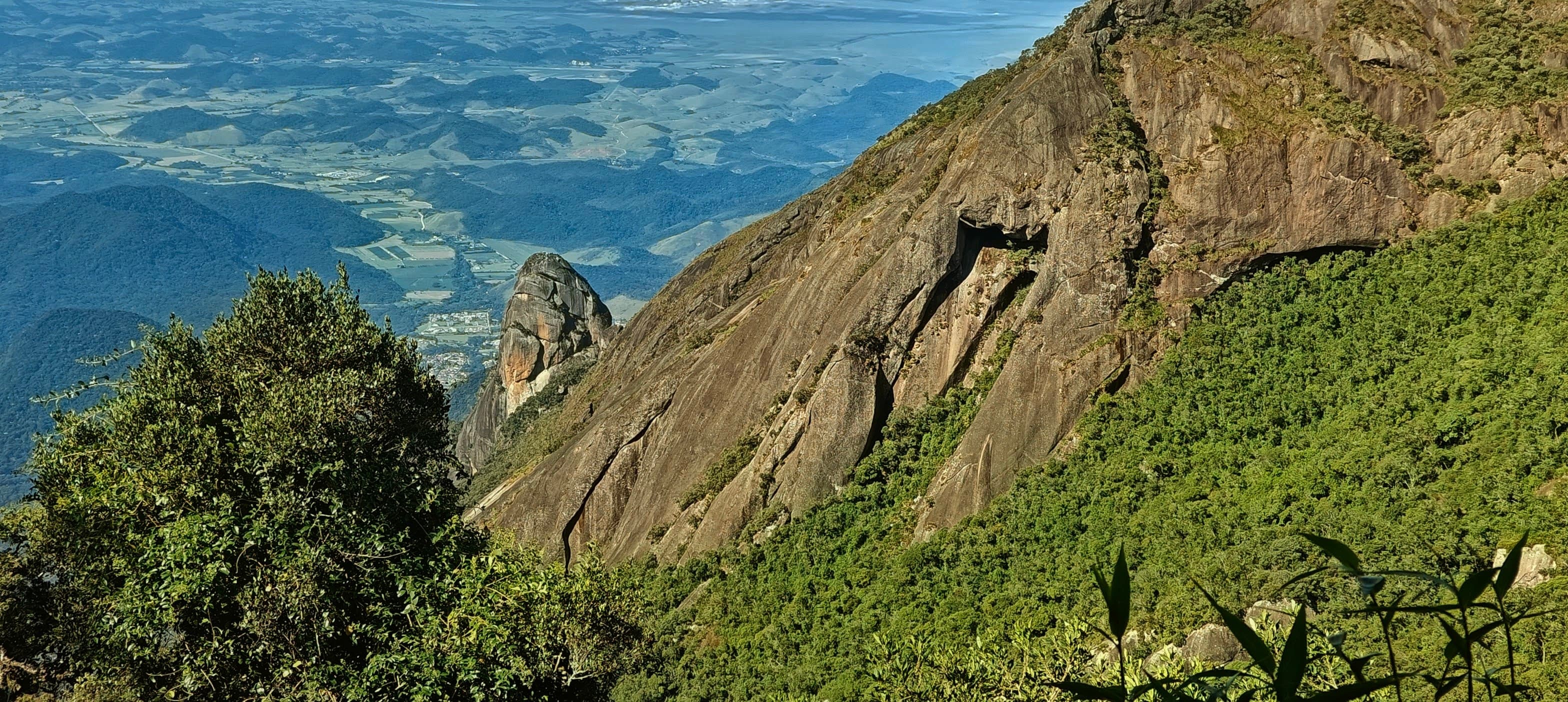 Steep granite slab rising above dense green forest on the upper slopes of Serra dos Órgãos.