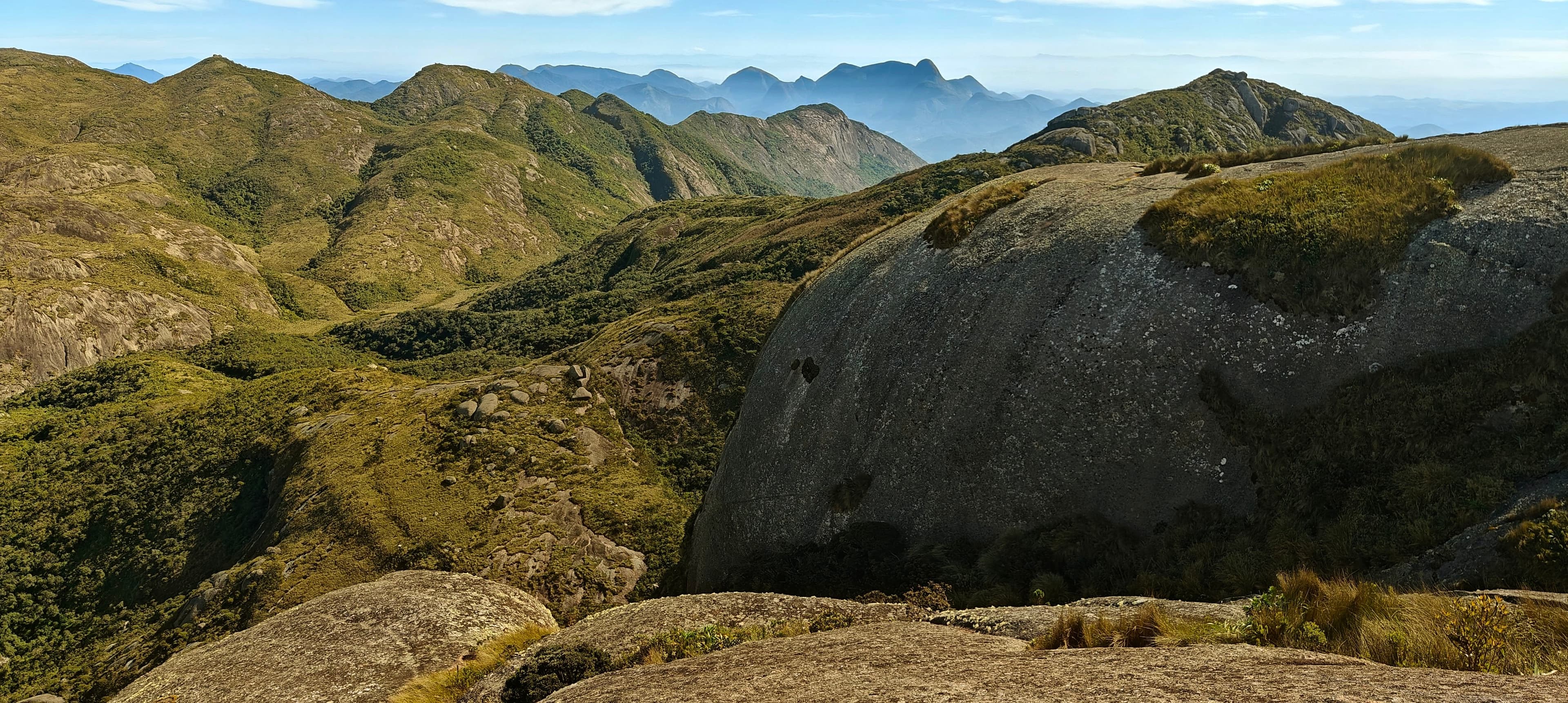 Open granite slabs and grassy ridges with a serrated mountain skyline in the distance.