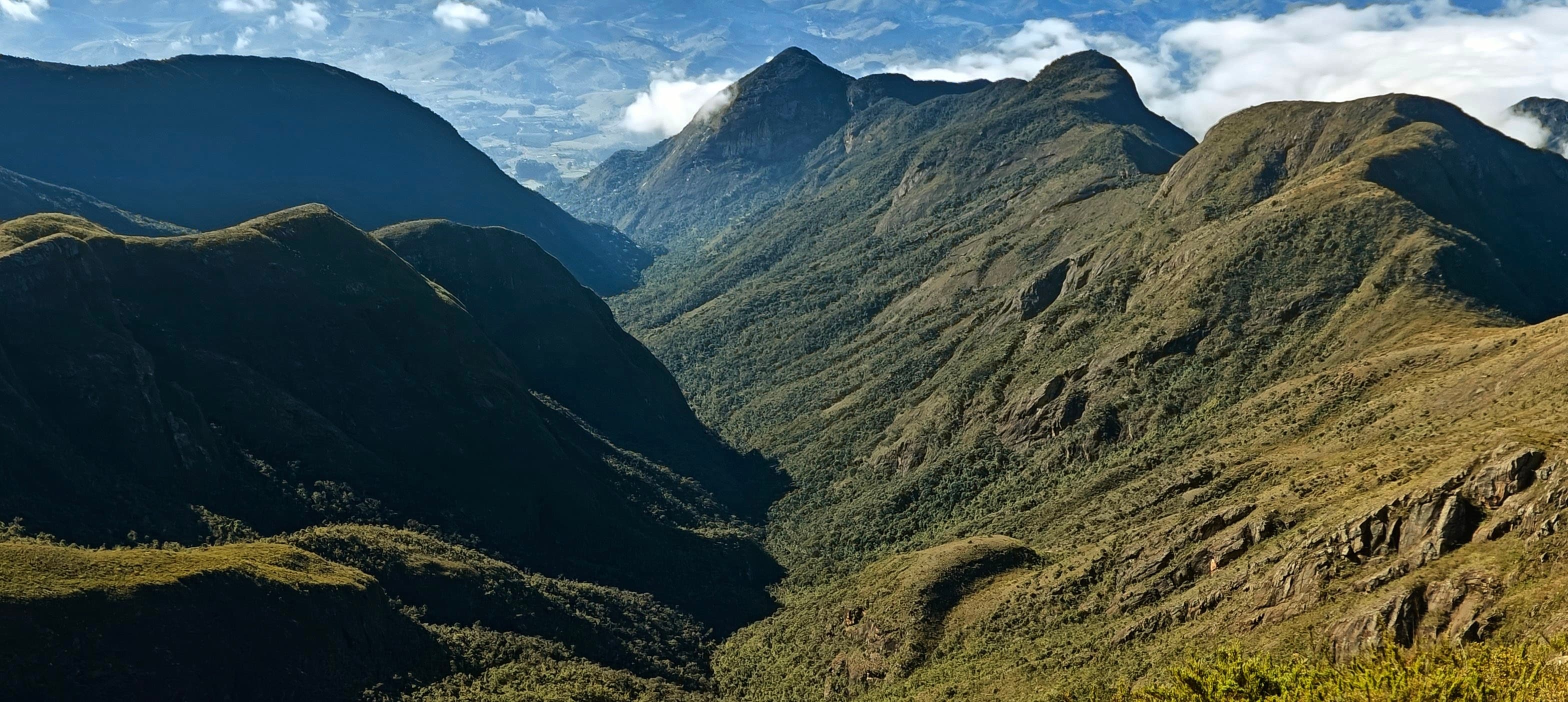 Rocky ridges and steep green slopes dropping into a deep valley in Caparaó National Park.