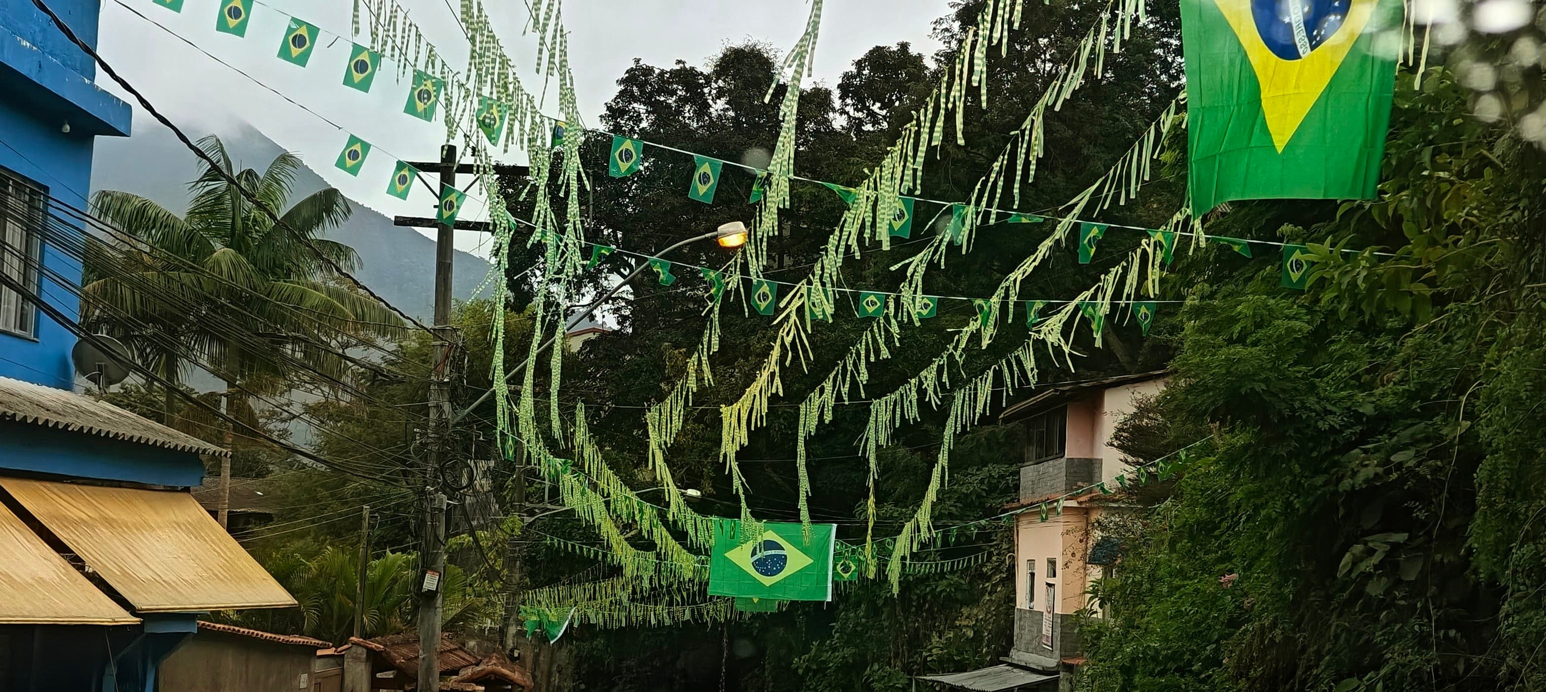 Brazilian flags and green-and-yellow decorations hanging above a narrow street.