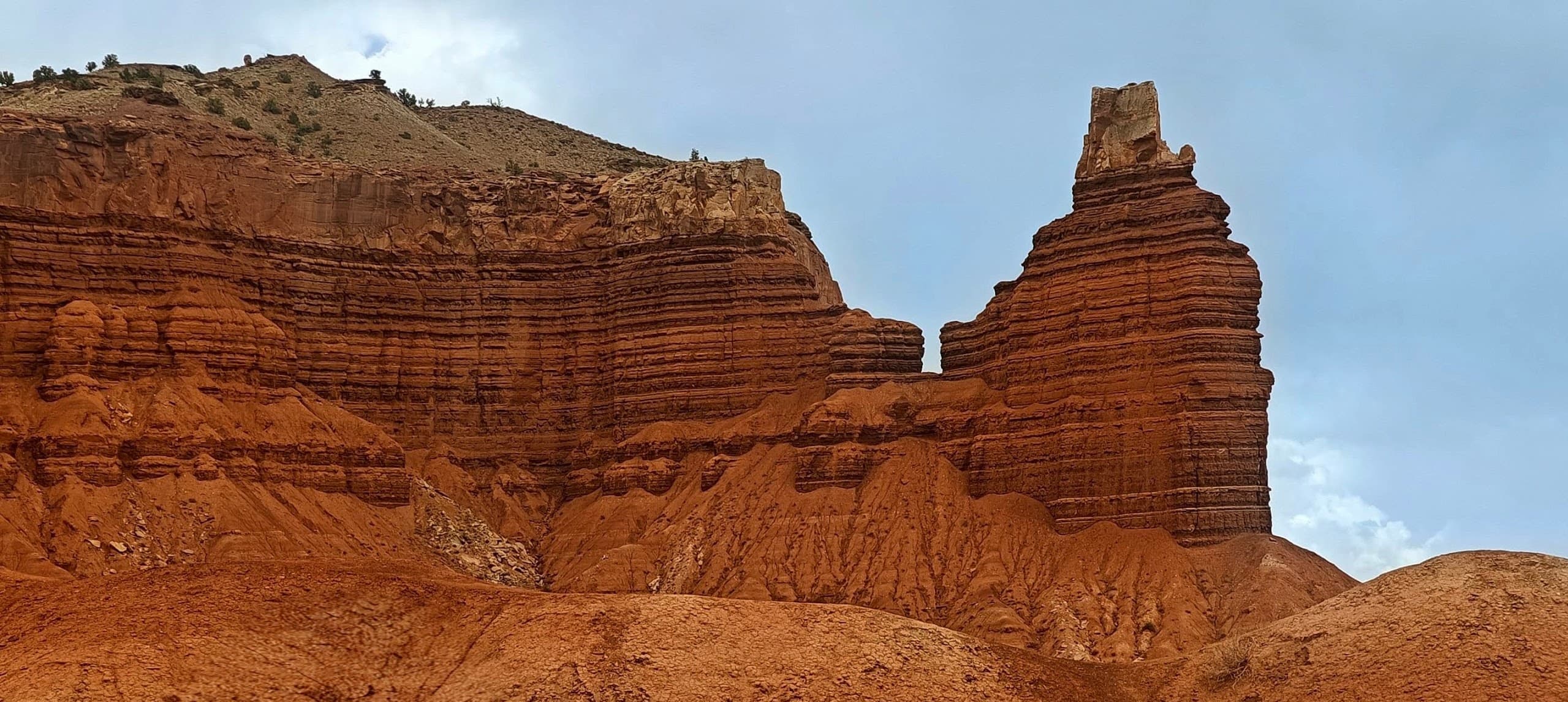 Chimney Rock rising as a narrow red sandstone tower beside layered cliffs in Capitol Reef National Park.