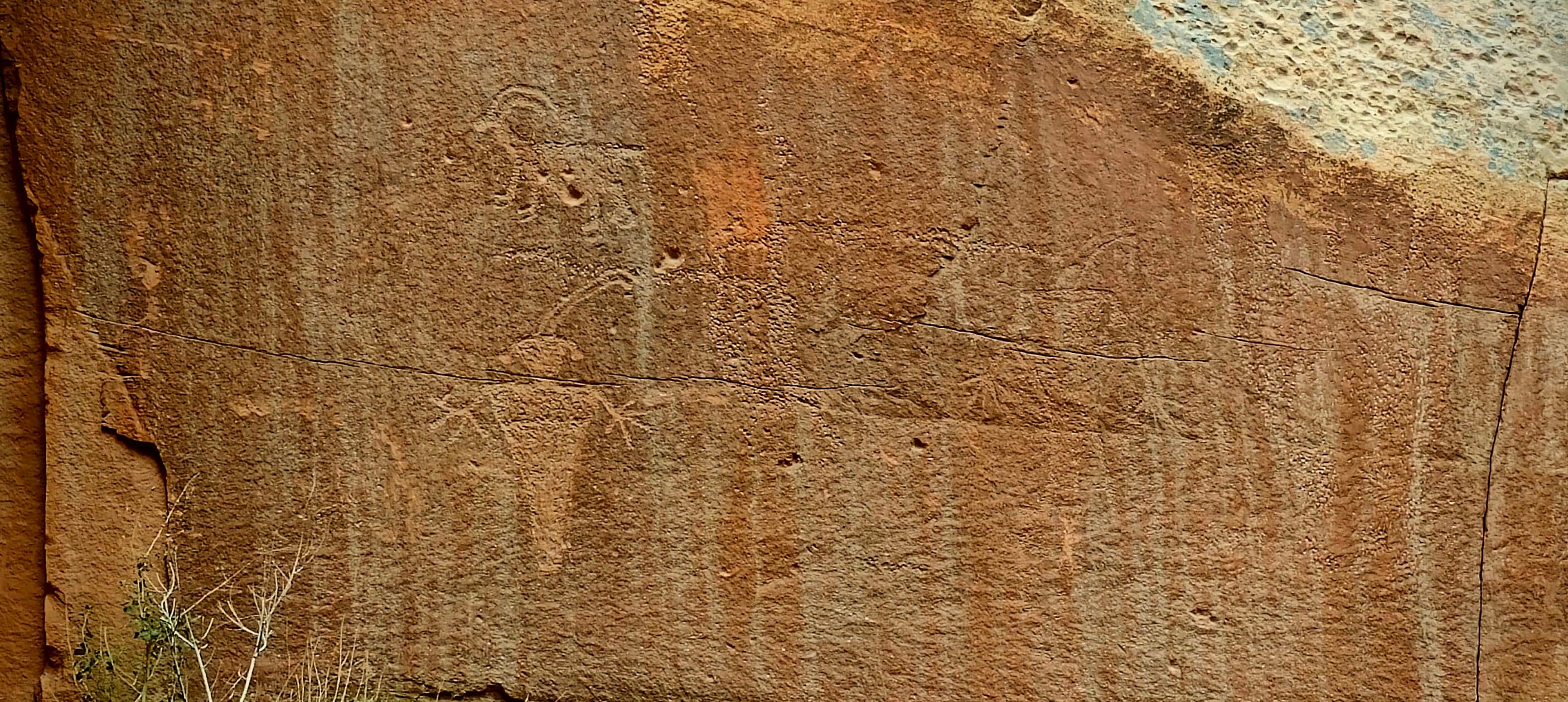 A weathered sandstone panel with faint Fremont Culture human-like and geometric petroglyph figures along Utah Highway 24.