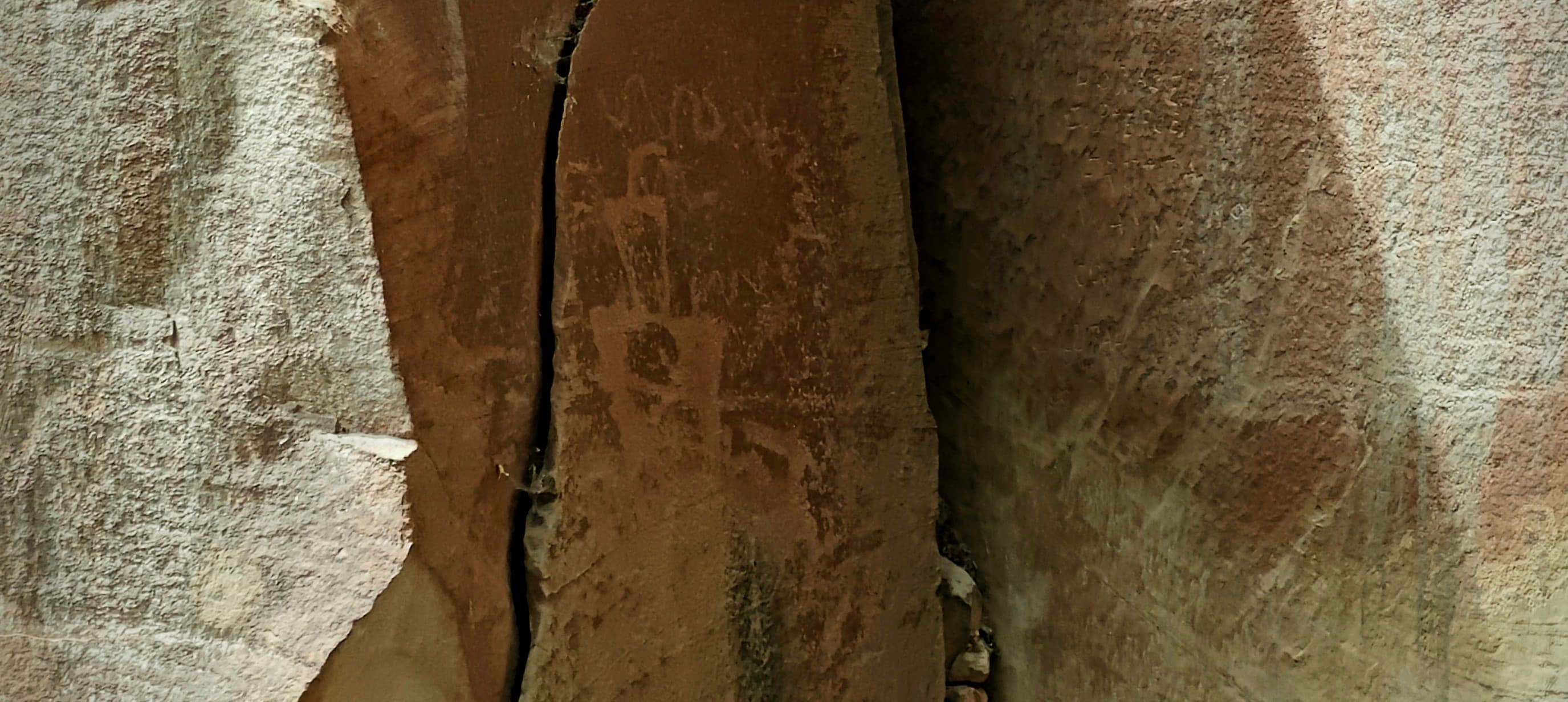Faint Fremont Culture petroglyph figures on a narrow vertical sandstone face in Capitol Reef National Park.