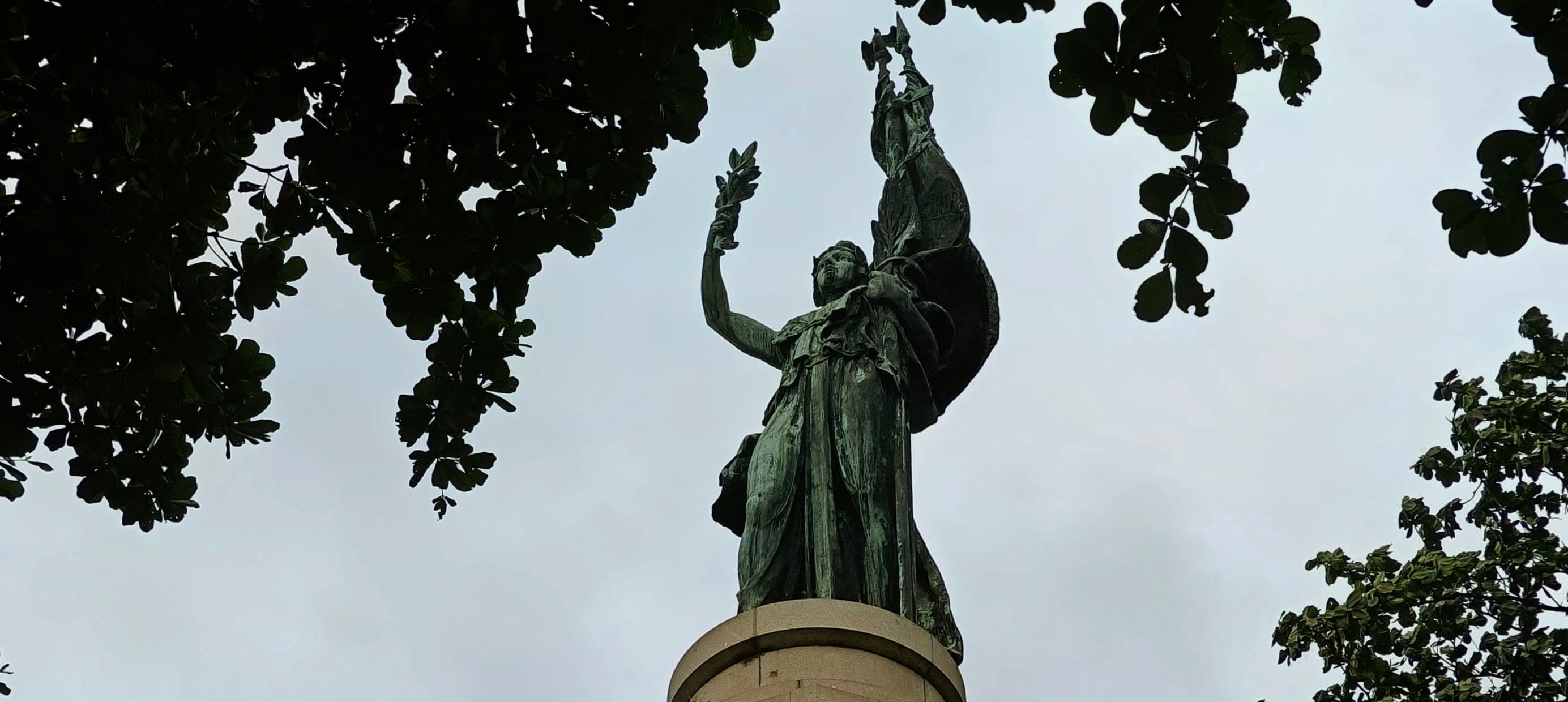 The tall Monument to Marshal Floriano Peixoto rises through trees in Cinelândia.