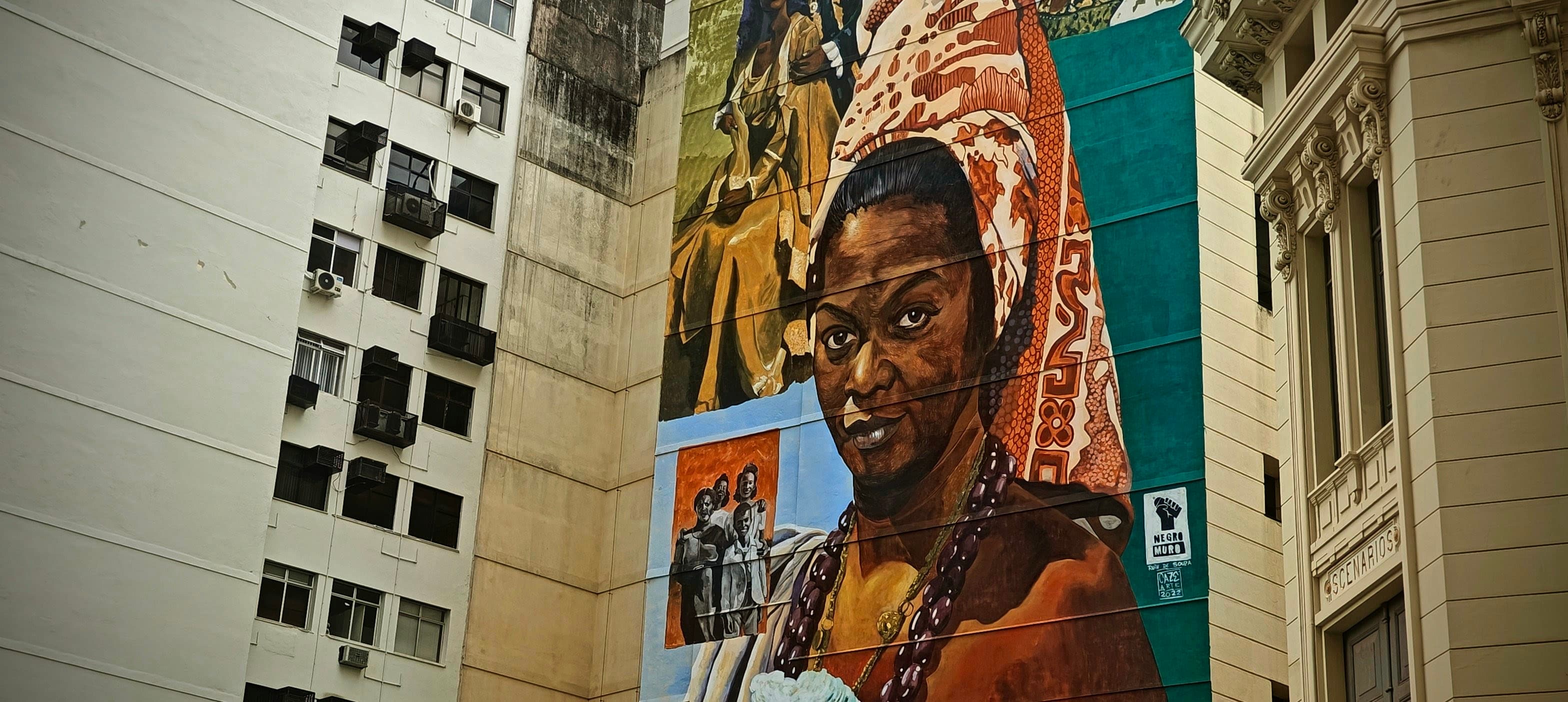 A large portrait mural of a Black woman fills the side of a building in central Rio.