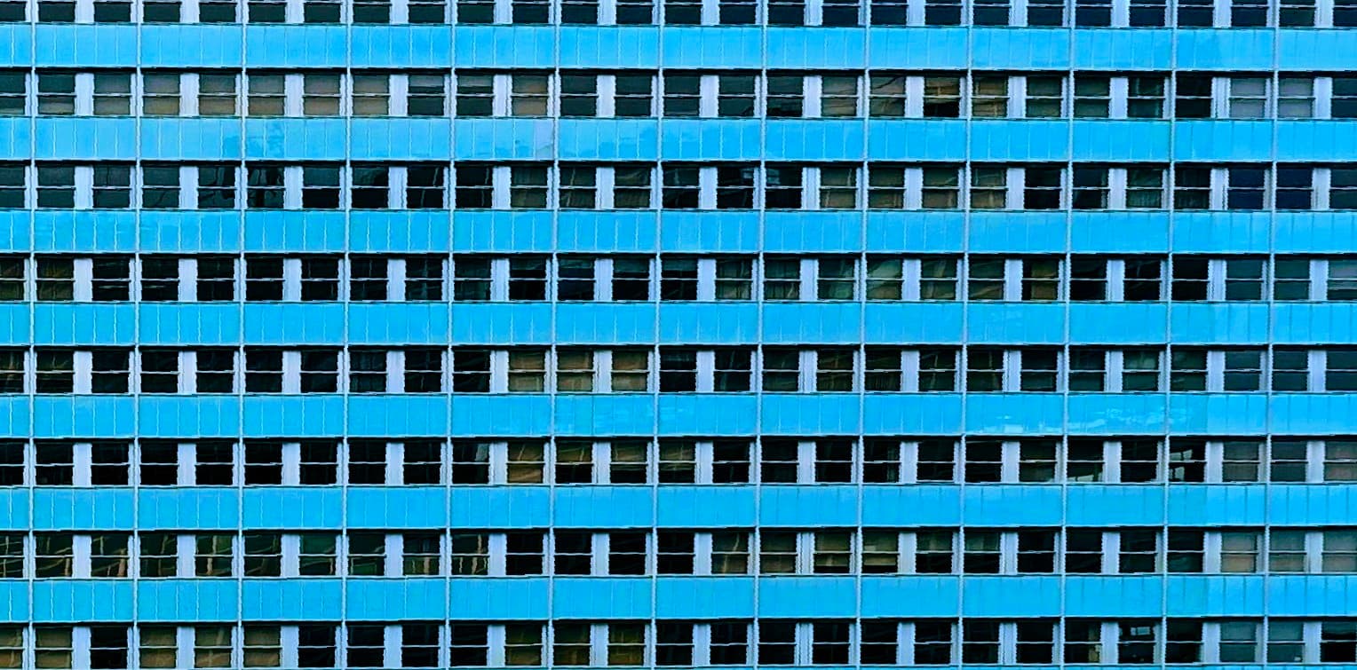 A blue office facade forms a dense repeating grid of identical windows.