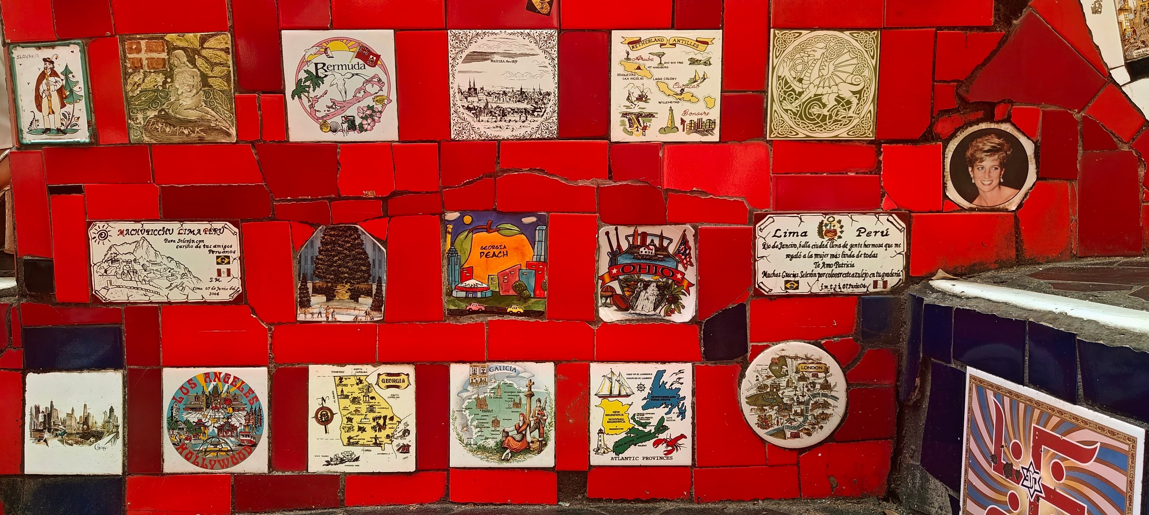 Rows of decorative ceramic tiles cover a red wall beside Escadaria Selarón.