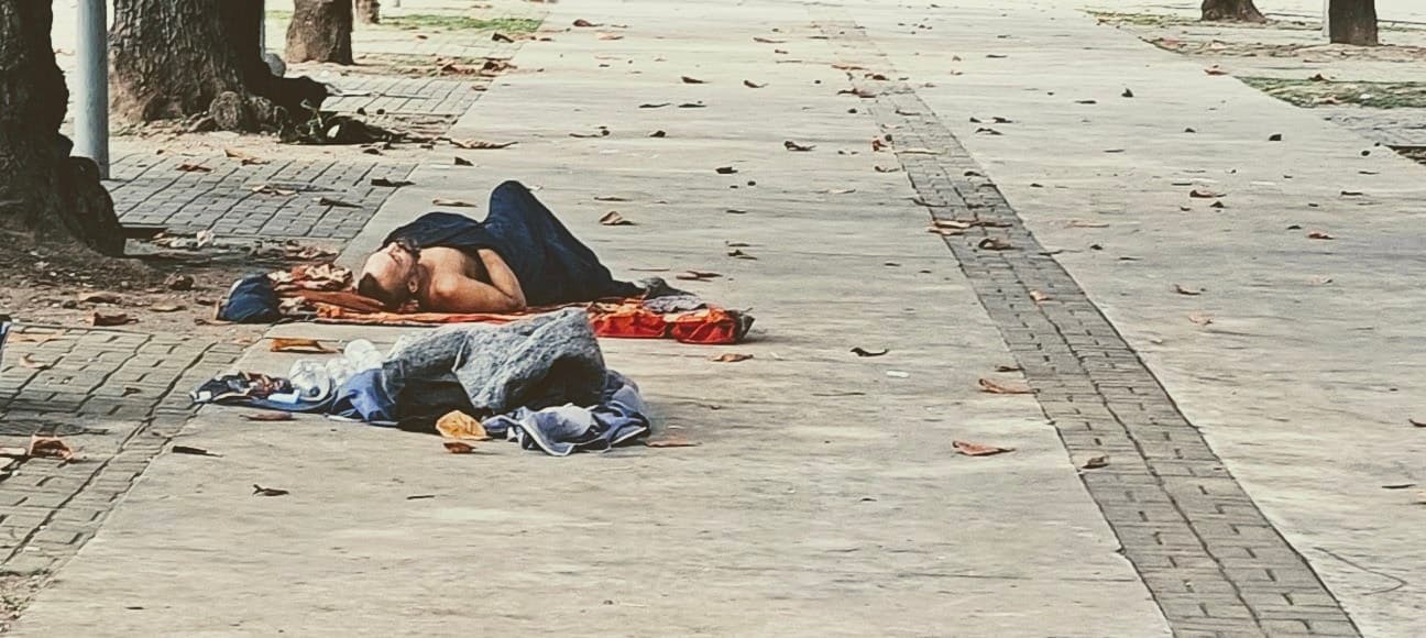Homeless people lie on blankets on a paved pedestrian area in central Rio.