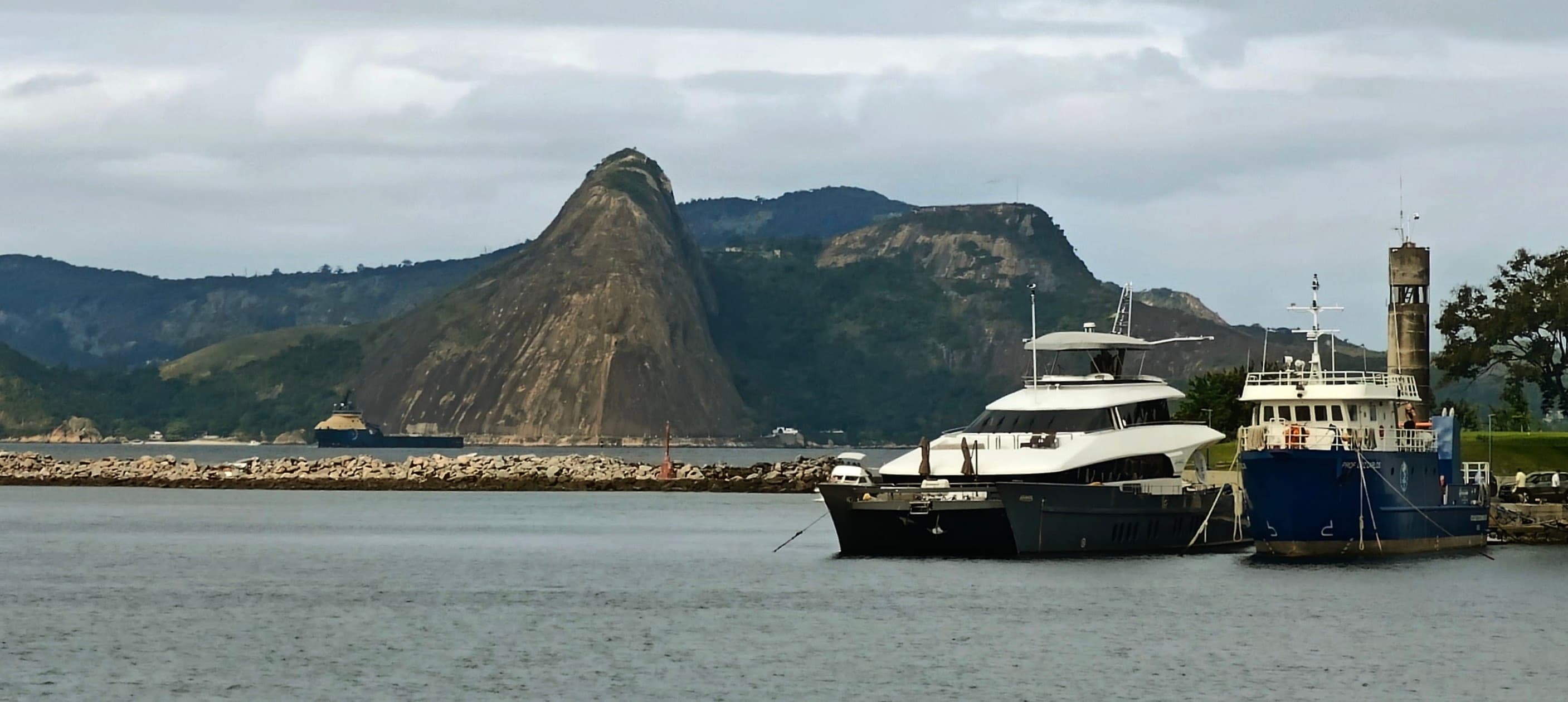 Sugarloaf Mountain rises beyond boats on Guanabara Bay under a cloudy sky.
