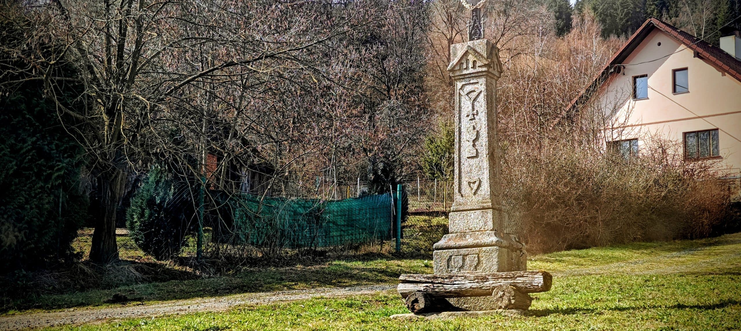 Stone village monument beside houses and leafless trees in Struhadlo.