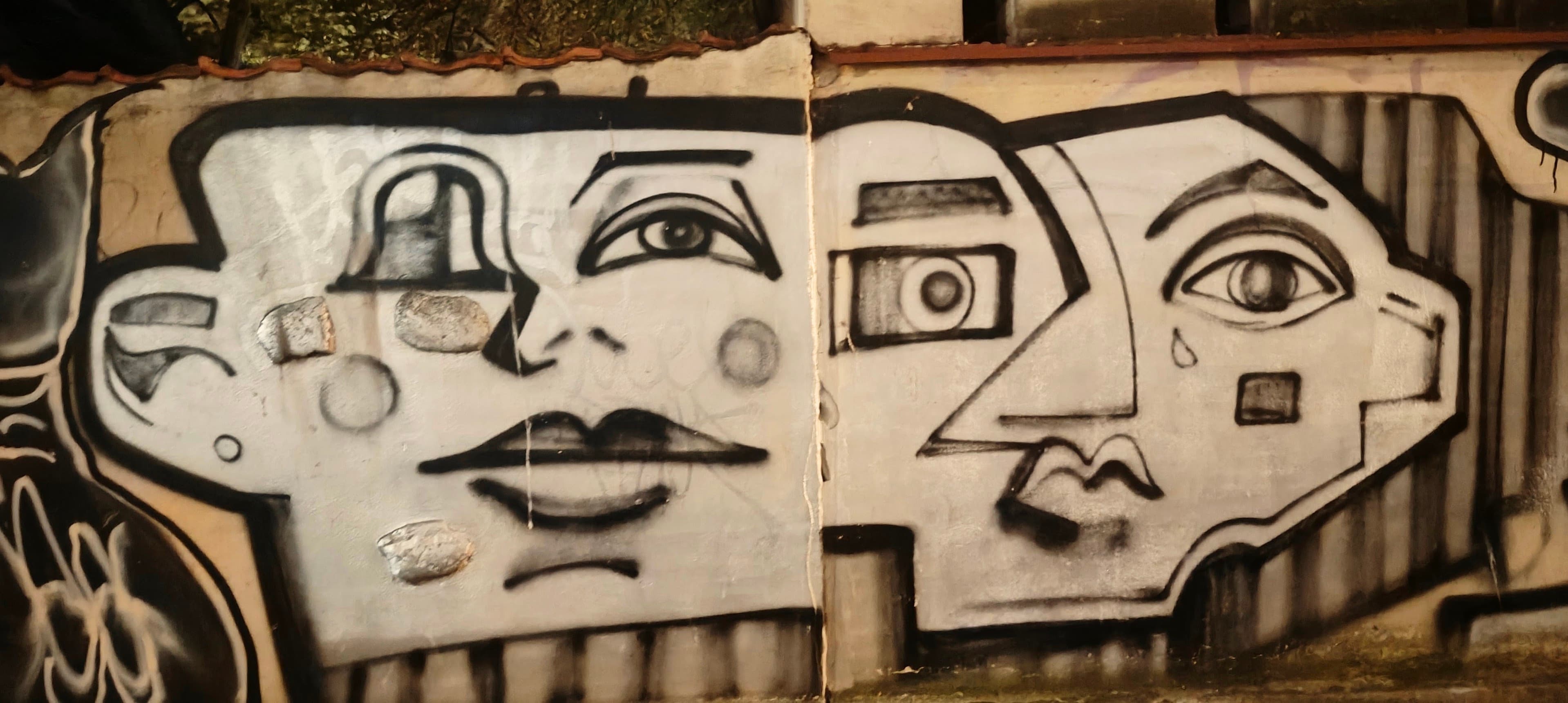 Black-and-white street art showing stylised faces painted across a metal shutter in Warsaw.