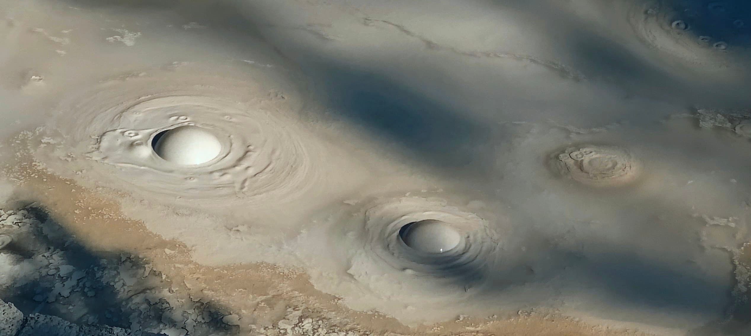 Circular bubbles rise and collapse in smooth grey geothermal mud.