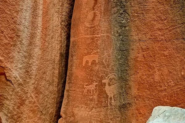 Faint Fremont Culture petroglyph figures visible in darker desert varnish along a narrow sandstone seam.