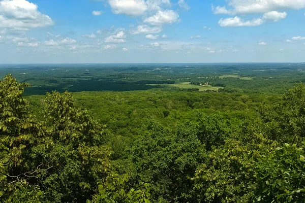 Wide view over forest, farmland and low ridges under a blue sky from an observation tower at Blue Mound.