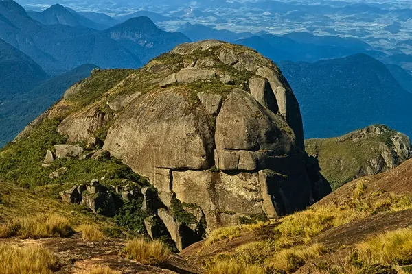 A massive rounded granite outcrop above forested ridges and distant valleys in Serra dos Órgãos.
