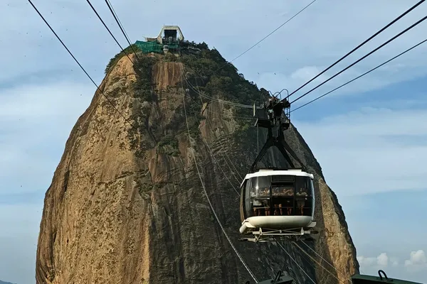 Cable car approaching Pão de Açúcar against the steep rock face in Rio de Janeiro.