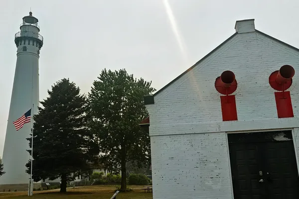 Wind Point Lighthouse beside a white fog-signal building with two red foghorns.